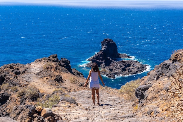 A young tourist walking on the cliff path on the descent to the black sand beach of Bujaren