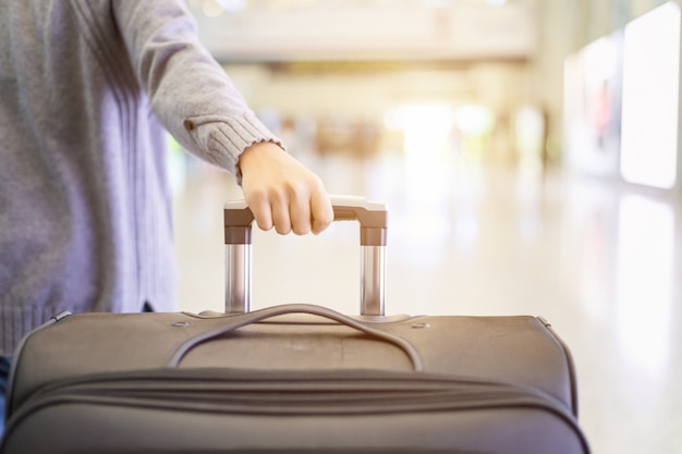 Young tourist walking and pulls luggage at the airport