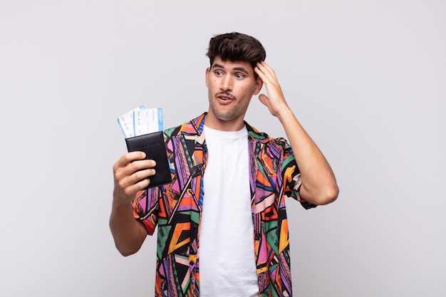 Young tourist with a passport looking happy, astonished and surprised, smiling and realizing amazing and incredible good news