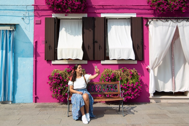 Foto una giovane donna turistica per le strade colorate di burano a venezia mentre sorride e visita la città italiana