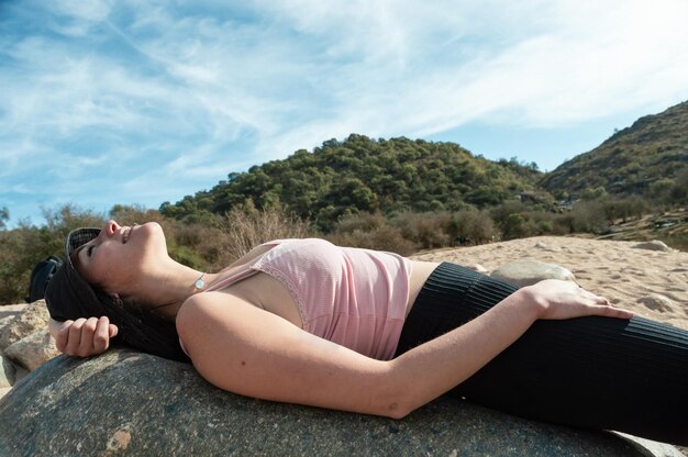 Молодая туристка лежит на скале и отдыхает