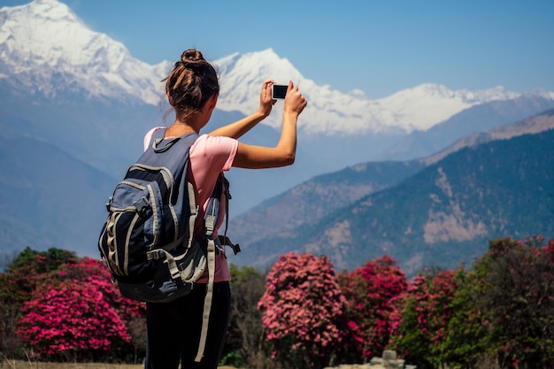 캠프 배낭을 메고 히말라야 산맥에서 풍경을 찍고 셀카를 찍는 젊은 관광 여성. 산에서 트레킹 개념