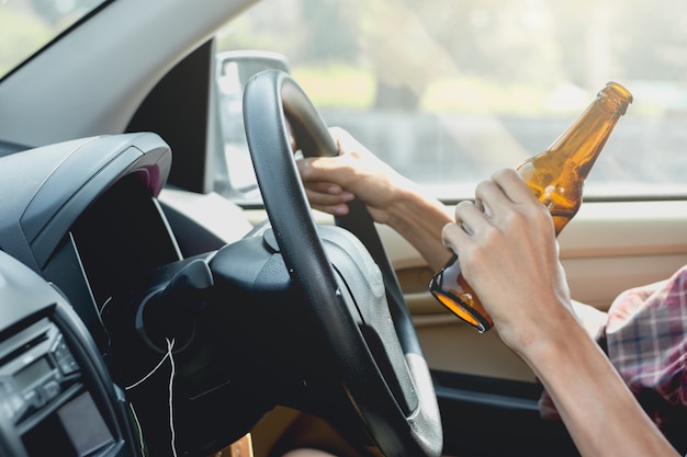 若い観光客がアルコールを飲みながら運転しています。