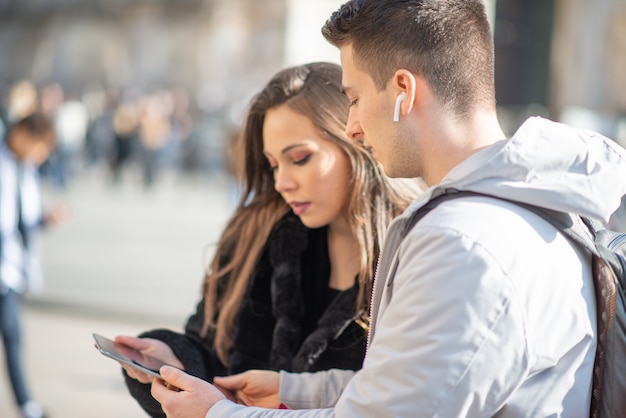 Coppia di giovani turisti che utilizza una tavoletta digitale in una città