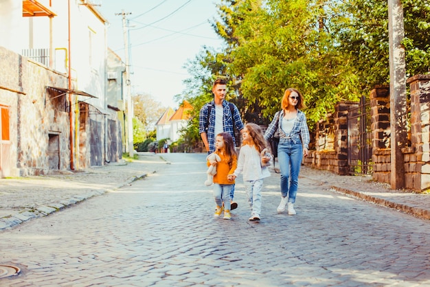 Семья молодых туристов с двумя прекрасными дочерьми гуляет по улице старого города во время весенних каникул.