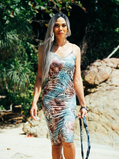 Photo young trans woman standing against plants and rocks