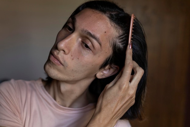 Молодой трансгендерный мужчина 22 лет расчесывает волосы Transgender Concept