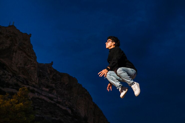 Photo young transgender man jumping outdoors at night