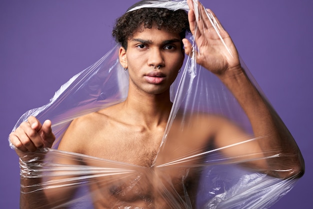 Молодой трансгендерный мужчина с разрушенным полиэтиленовым пакетом на обнаженном мускулистом теле трансгендерный мужчина может дышать