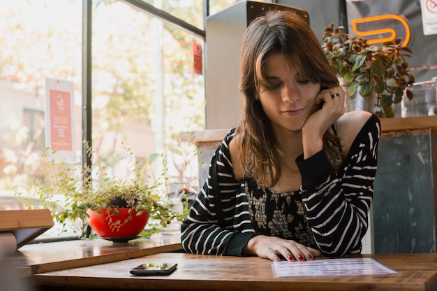 何を食べるかを考えてレストランのメニューを読んで座っている若いトランスジェンダーの女性