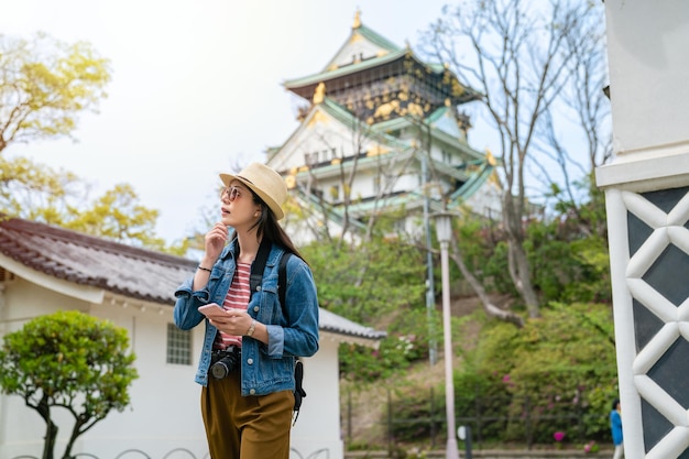 Young travel woman searching the place by phone while visiting
in old tradtional japanese castle.