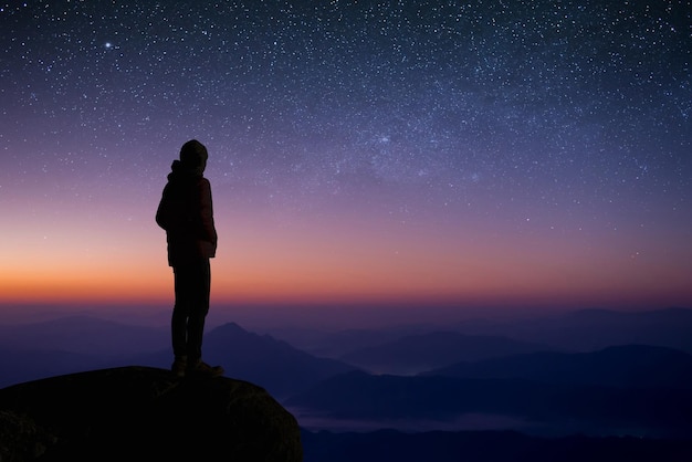 Foto giovane viaggiatore e zaino in spalla osservava la stella e la via lattea da solo in cima alla montagna gli piaceva viaggiare e quando raggiunse la vetta ebbe successo