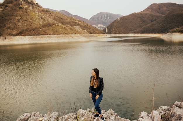 Young traveler girl standing on a stones near lake and mountains in Italy, Europe