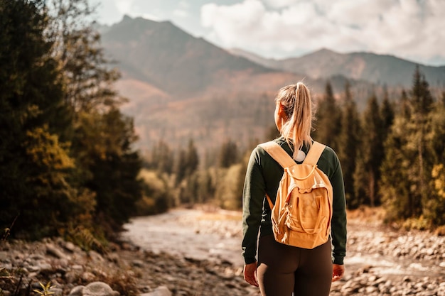 Young traveler hiking girl with backpacks hiking in nature\
sunset mood sunny landscape bielovodska walley slovakia high\
tatras