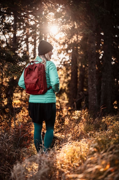 Young traveler hiking girl with backpacks Hiking in nature Sunset mood Sunny landscape Tourist traveler on background view mockup Hiker looking sunlight in trip