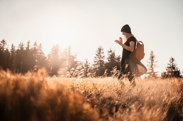 Young traveler hiking girl with backpacks hiking in nature\
sunset mood sunny landscape tourist traveler on background view\
mockup hiker looking sunlight in trip