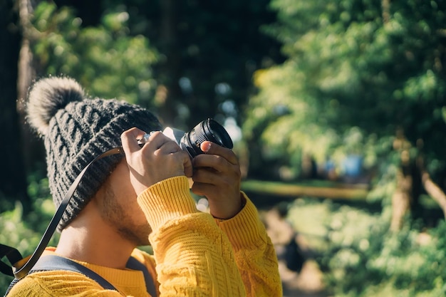 Young traveler holding an analog camera taking a photo nature travel concept