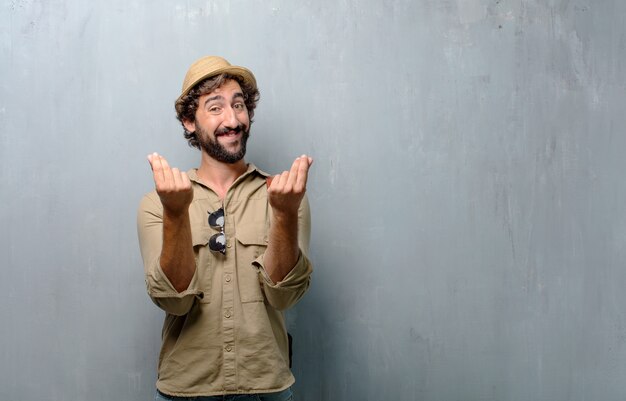 Young traveler man looking happy, proud and satisfied, gesturing cash or money