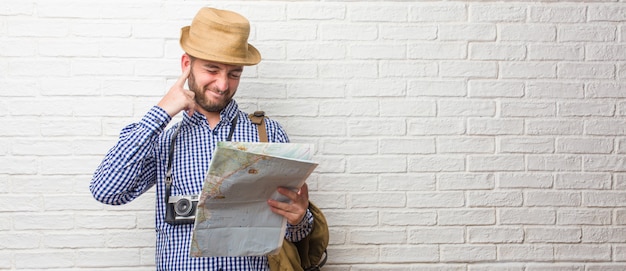 Young traveler man wearing backpack and a vintage camera covering ears with hands