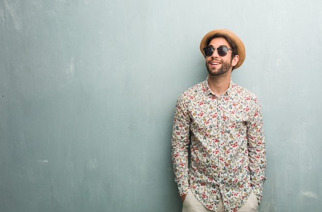 Young traveler man wearing a colorful shirt looking up, thinking of something fun and havi