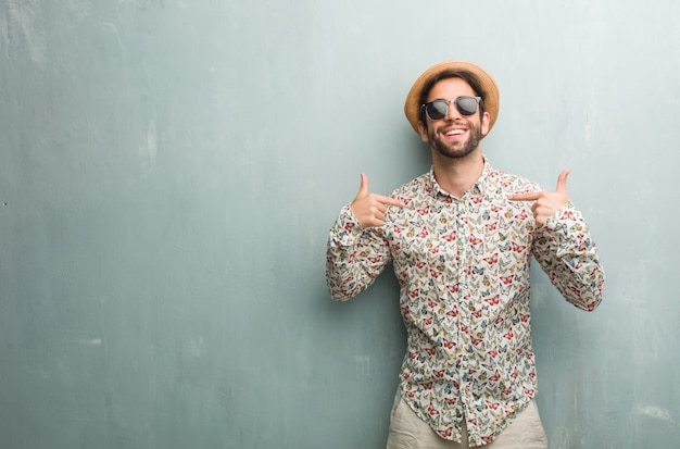 Giovane uomo viaggiatore che indossa una camicia colorata orgoglioso e fiducioso, che punta le dita