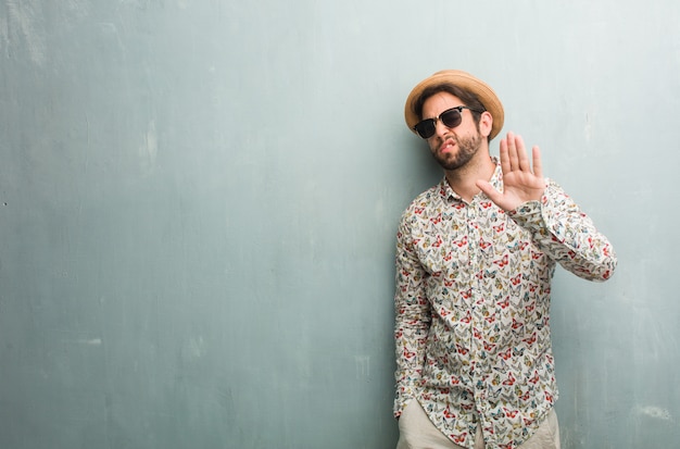 Young traveler man wearing a colorful shirt serious and determined