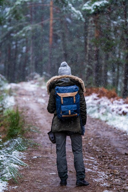 Photo young traveler in mountain gear captures scenic winter landscape with camera