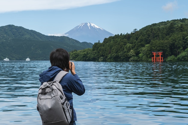 Young traveler takeing photo of  Hakone shrine with mt.Fuji at  lake Ashi, Japan