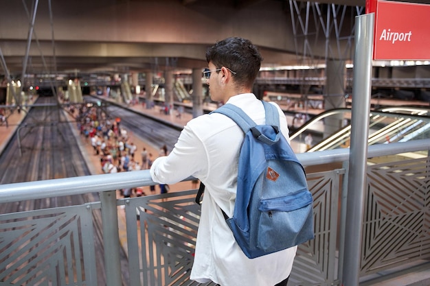 バックパックを持って駅で待っている若い旅行者