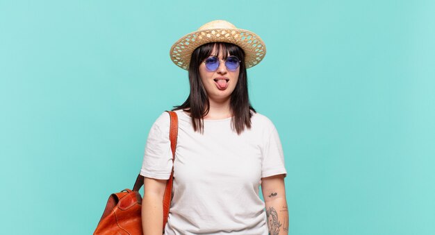 Young traveler woman feeling disgusted and irritated, sticking tongue out, disliking something nasty and yucky