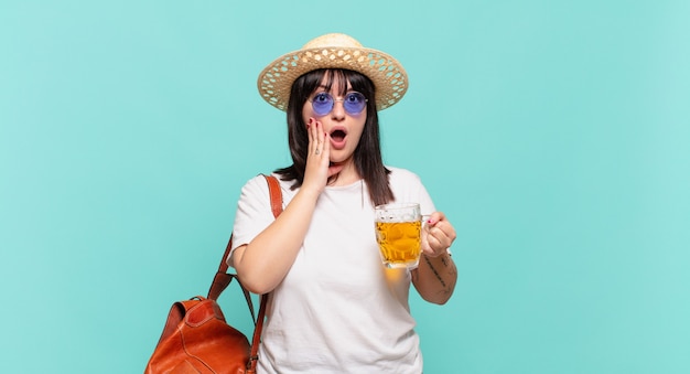 Young traveler woman feeling shocked and scared, looking terrified with open mouth and hands on cheeks