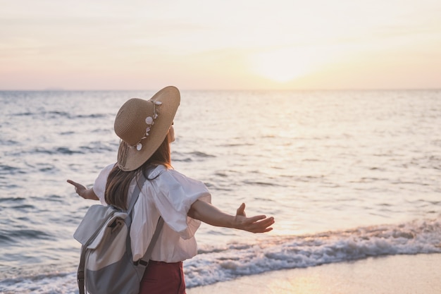 Young traveler woman relaxing on tropical beach at sunset