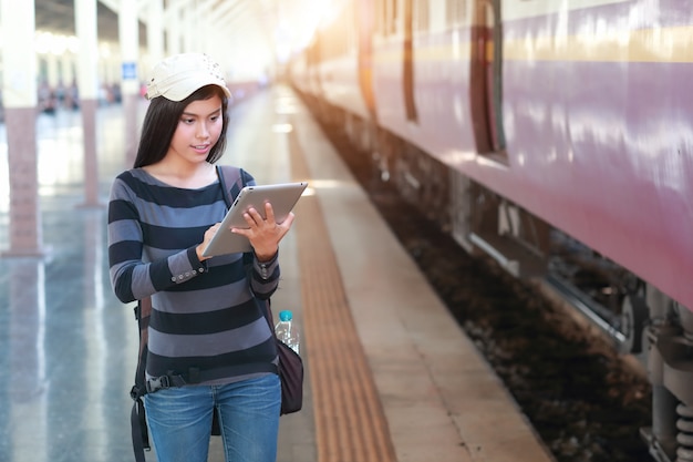 Young traveler woman with backpack using tablet during traveling on holiday 