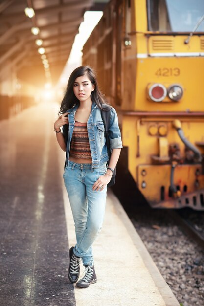 Young traveler woman with backpack waiting for train