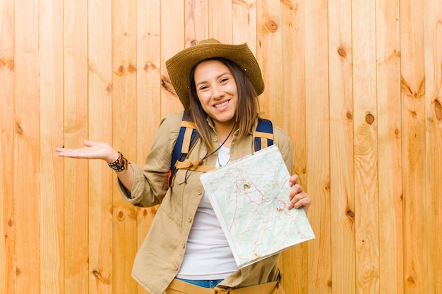 Young traveler woman with a map against wood wall