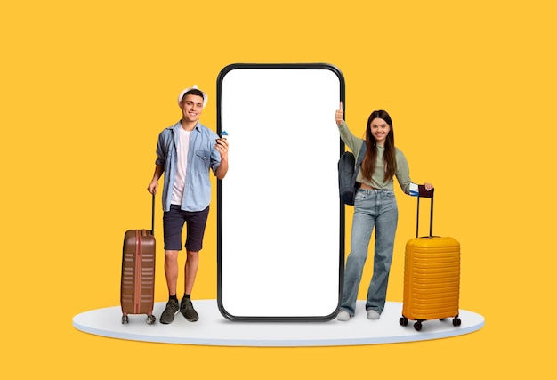 Young travelers with suitcases next to large blank phone