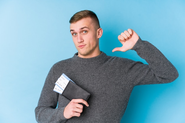 Young traveller man holding a boarding pass feels proud and self confident, example to follow.