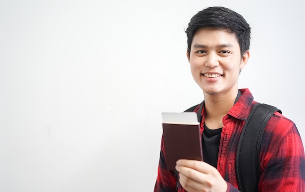 Young traveller man smiles and holds passport with ticket