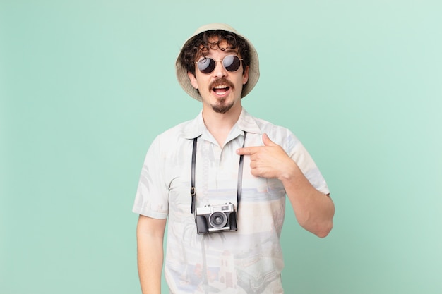 Young traveller tourist looking shocked and surprised with mouth wide open, pointing to self