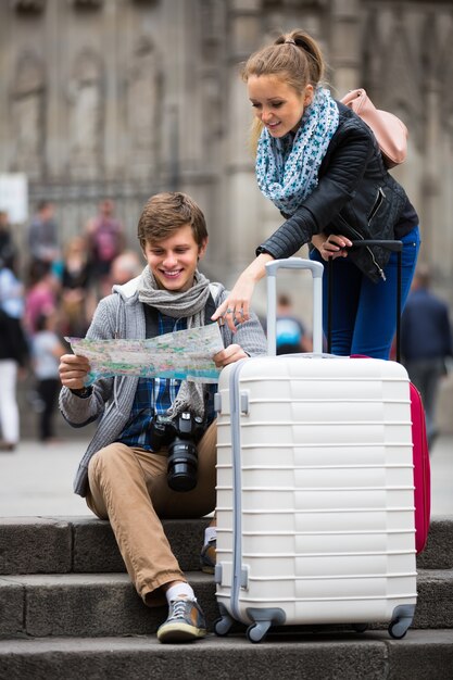 Young travellers with city map at street