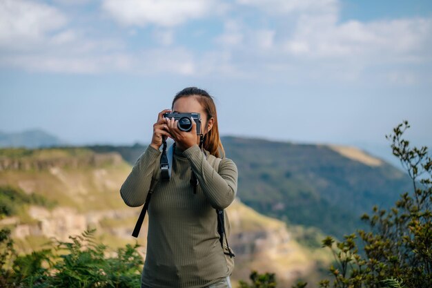 젊은 트레킹 여성은 바위산 정상에서 카메라 사진을 사용합니다.