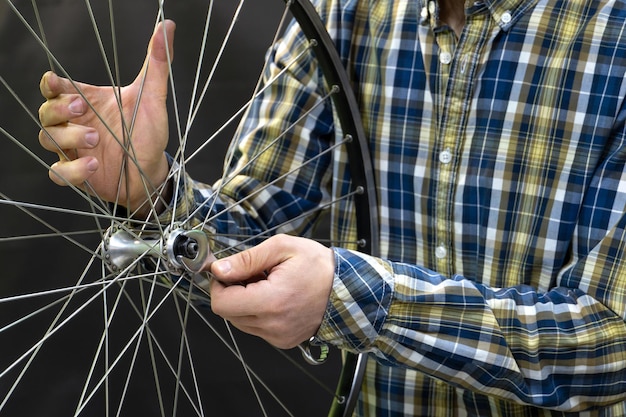 Young trendy bike mechanic in a nice shirt repairs of the wheel
road bike professional bike repair in studio on black background
wheel and hands of mechanic closeup front wheel hub repair