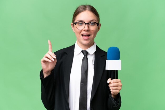 Young TV presenter caucasian woman over isolated background pointing up a great idea