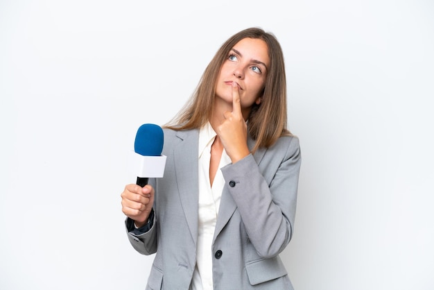 Young TV presenter caucasian woman isolated on white background having doubts while looking up