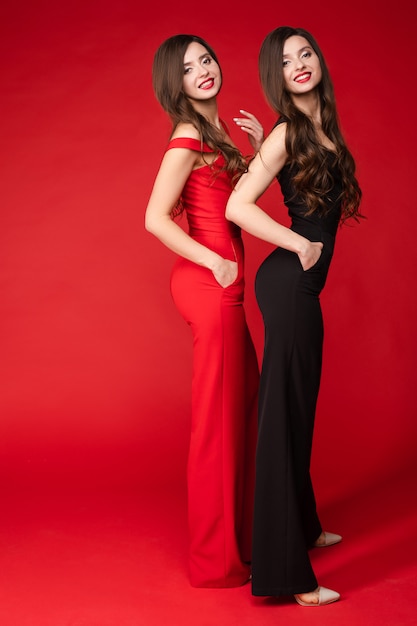 Young twins wearing similar black and red outfits and posing