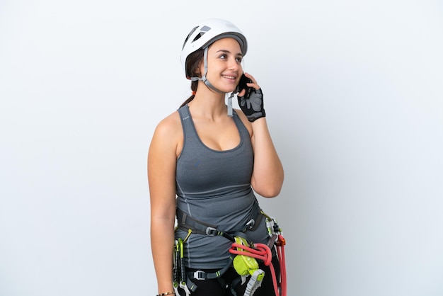 Young Ukrainian rock climber woman isolated on white background keeping a conversation with the mobile phone