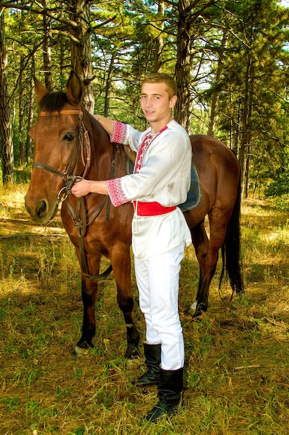 Foto giovane ucraino con un cavallo nella foresta