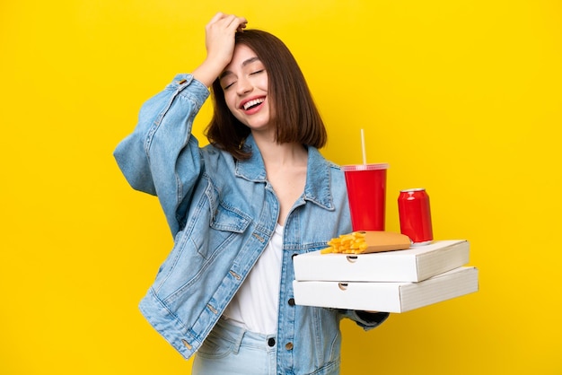 Young Ukrainian woman holding fast food isolated on yellow background has realized something and intending the solution