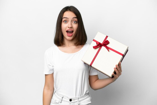 Young Ukrainian woman holding a gift isolated on white background with surprise and shocked facial expression