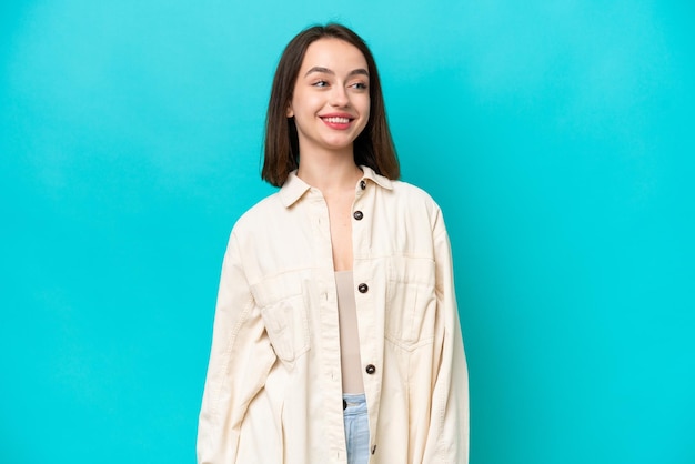 Young Ukrainian woman isolated on blue background looking side